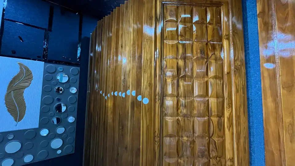 High-gloss carved wood door panel beside decorative wall panels in the showroom