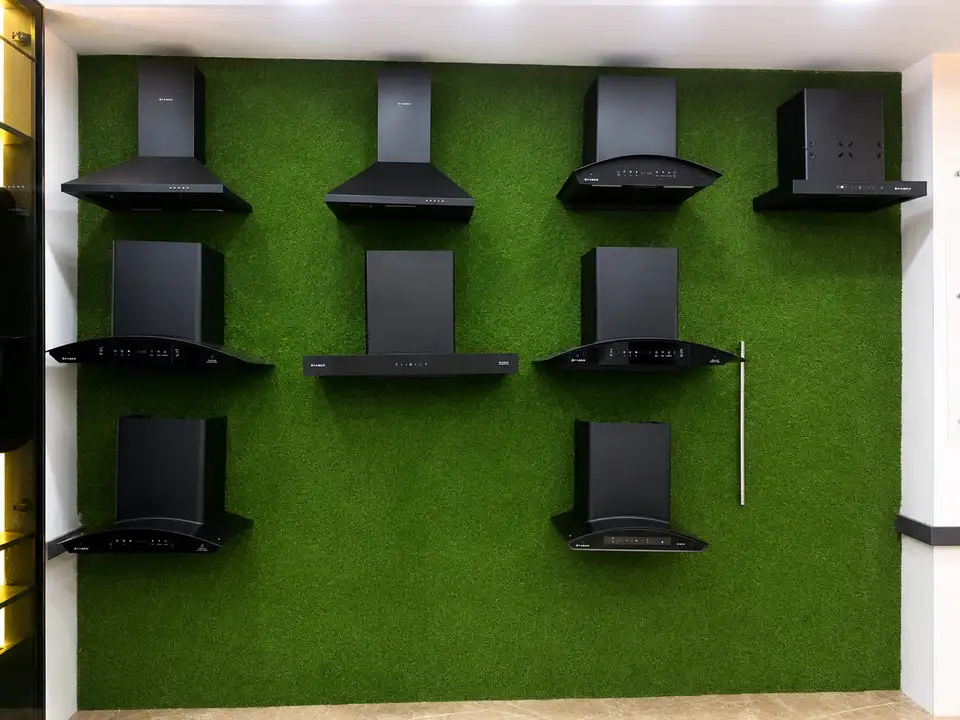 Faber kitchen chimneys displayed on a green turf wall in the showroom