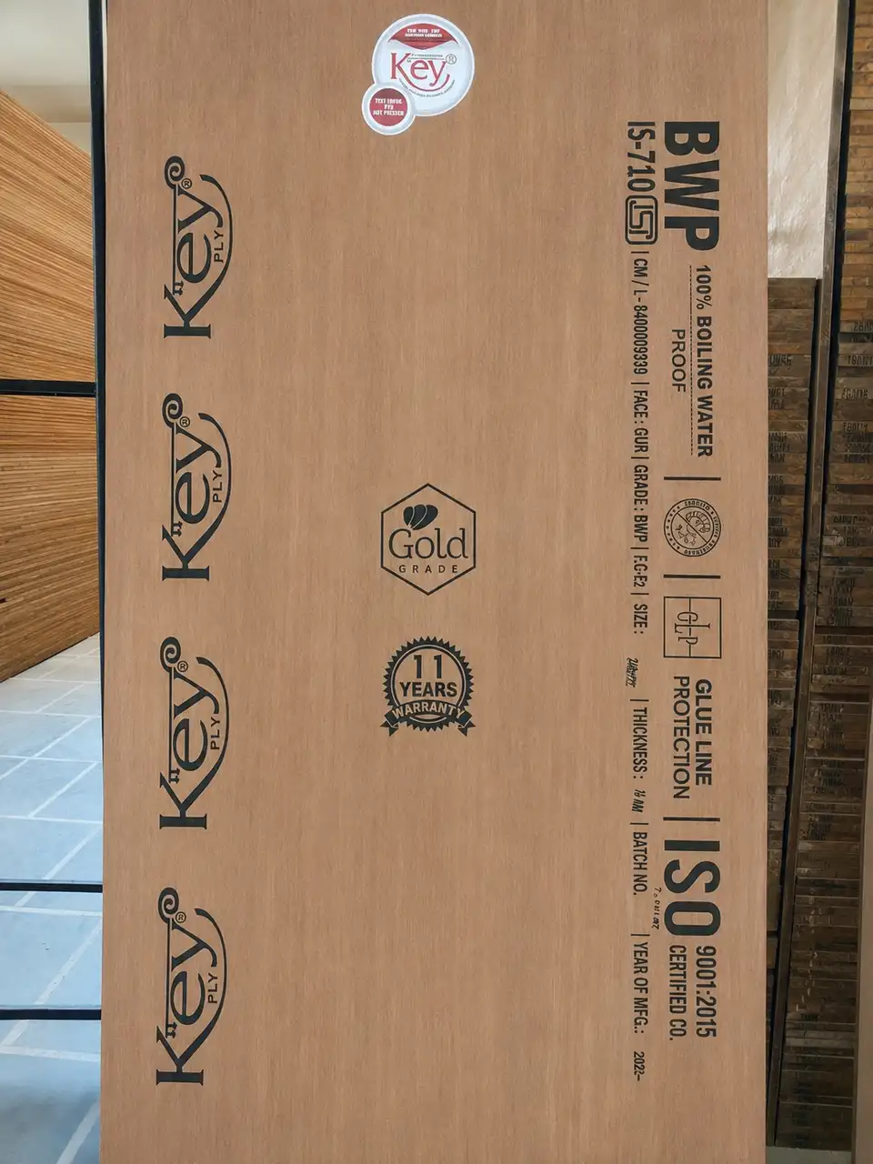 Key Ply BWP boiling-water-proof plywood sheet stamped IS-710, with plywood stacks behind